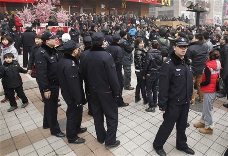 In this photo taken on Sunday, police officers watch people gathering in front of a McDonald's restaurant that was a planned protest site for "Jasmine Revolution" in Beijing.